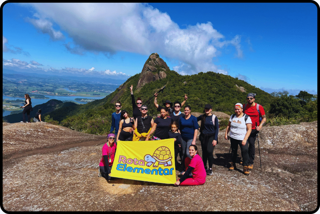 Rota Elementar no Pico do Lopo com bandeira amarela, montanhas ao fundo e céu azul