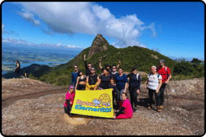  Rota Elementar no Pico do Lopo com bandeira amarela, montanhas ao fundo e céu azul