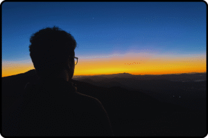 Silhueta de pessoa observando o amanhecer no Pico do Lopo durante a primeira trilha da Rota Elementar