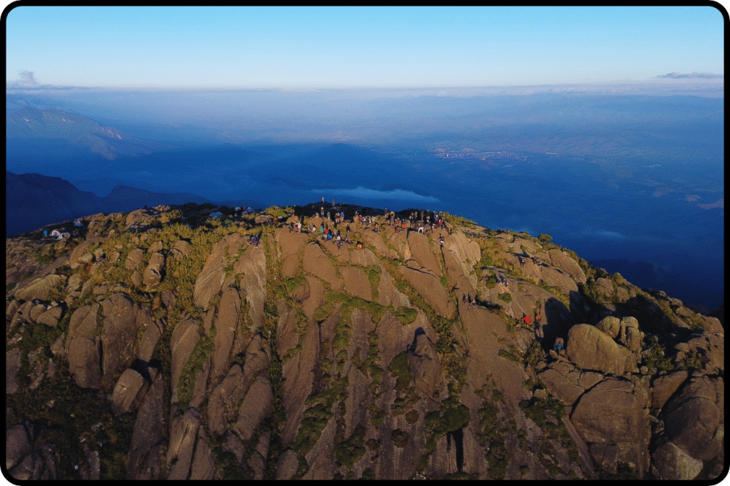Vista do cume com dimensão da Altura do Pico dos Marins ao amanhecer, com rochas douradas e céu azul profundo