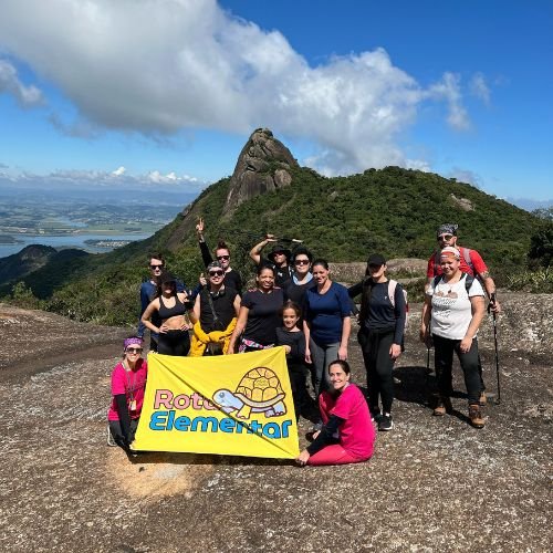 Grupo no Pico do Lopo com bandeira da Rota Elementar durante experiência de montanhismo na Serra da Mantiqueira