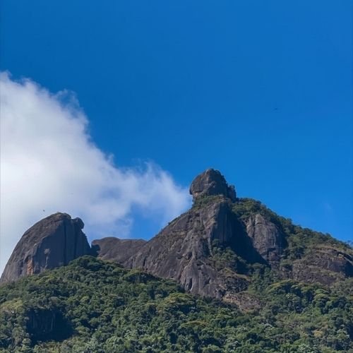 Silhueta imponente da montanha da Pedra Selada em Visconde de Mauá sob céu azul limpo, exibindo o cume rochoso característico e encostas verdes cobertas por floresta densa de Mata Atlântica de altitude na Serra da Mantiqueira, em Resende, RJ.