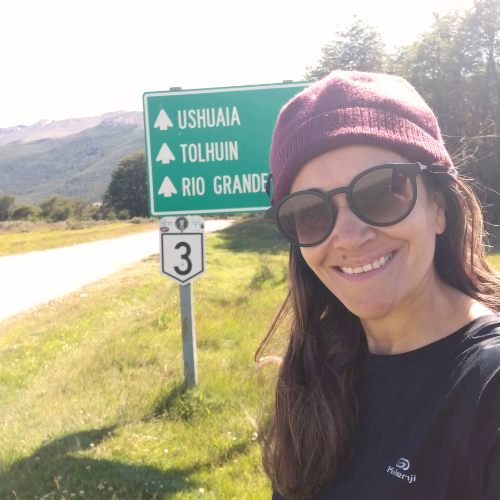 Viajante ao lado de placa de sinalização em estrada durante jornada internacional.